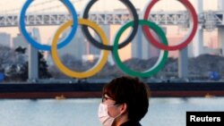 Seorang pria mengenakan masker di tengah wabah COVID-19 di depan cincin Olimpiade raksasa di Tokyo, Jepang, 13 Januari 2021. (Foto: REUTERS/Kim Kyung-Hoon)