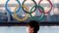 Seorang pria mengenakan masker di tengah wabah COVID-19 di depan cincin Olimpiade raksasa di Tokyo, Jepang, 13 Januari 2021. (Foto: REUTERS/Kim Kyung-Hoon)