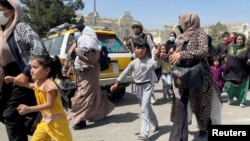 Des femmes avec leurs enfants tentent de pénétrer à l'intérieur de l'aéroport international Hamid Karzai de Kaboul, en Afghanistan, le 16 août 2021.