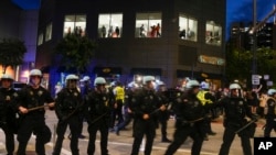 People watch from the second floor of a building as police block the street during a demonstration near the Israeli Consulate during the Democratic National Convention Aug. 20, 2024, in Chicago.