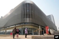 people walk past an Evergrande complex with a shuttered Evergrande in Beijing, Monday, Jan. 29, 2024. Chinese property developer China Evergrande Group on Monday was ordered to liquidate by a Hong Kong court. (AP Photo/Ng Han Guan)