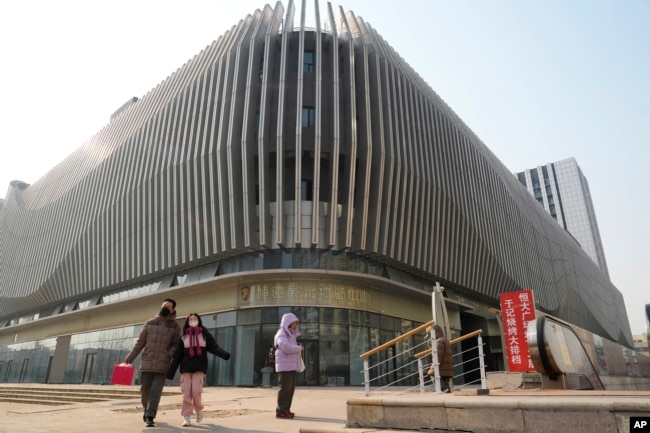 people walk past an Evergrande complex with a shuttered Evergrande in Beijing, Monday, Jan. 29, 2024. Chinese property developer China Evergrande Group on Monday was ordered to liquidate by a Hong Kong court. (AP Photo/Ng Han Guan)