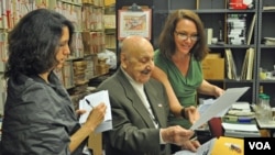 Leo Sarkisian and Heather Maxwell (right), the host of VOA's "Music Time in Africa," look over listener mail in the library that houses his vast collection of African music. Looking on is Washington Post reporter Tara Bahrampour.