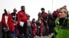 Des migrants font la queue en attendant que le bus soit pris en charge, à Dungeness, sur la côte sud-est de l'Angleterre, le 16 août 2023, après avoir été récupérés en mer par un canot de sauvetage de la Royal National Lifeboat Institution (RNLI) (Photo de HENRY NICHOLLS / AFP)