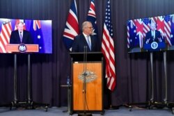 Australia's Prime Minister Scott Morrison, center, appears on stage with video links to Britain's Prime Minister Boris Johnson, left, and U.S. President Joe Biden at a joint press conference at Parliament House in Canberra, Sept. 16, 2021.