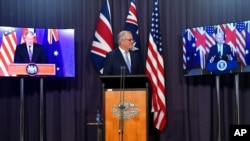 Australia's Prime Minister Scott Morrison, center, appears on stage with video links to Britain's Prime Minister Boris Johnson, left, and U.S. President Joe Biden at a joint press conference at Parliament House in Canberra, Sept. 16, 2021.