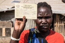 Shejirina Moni shows her measles vaccination immunization card for one of her children. Her children were vaccinated against measles in February as part of a nationwide campaign. (Chika Oduah/VOA)