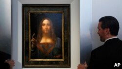 Guardias de seguridad vigilan "Salvator Mundi" de Leonardo da Vinci durante una conferencia de prensa en la casa de subastas Christie en Nueva York, el martes, 10 de octubre de 2017.