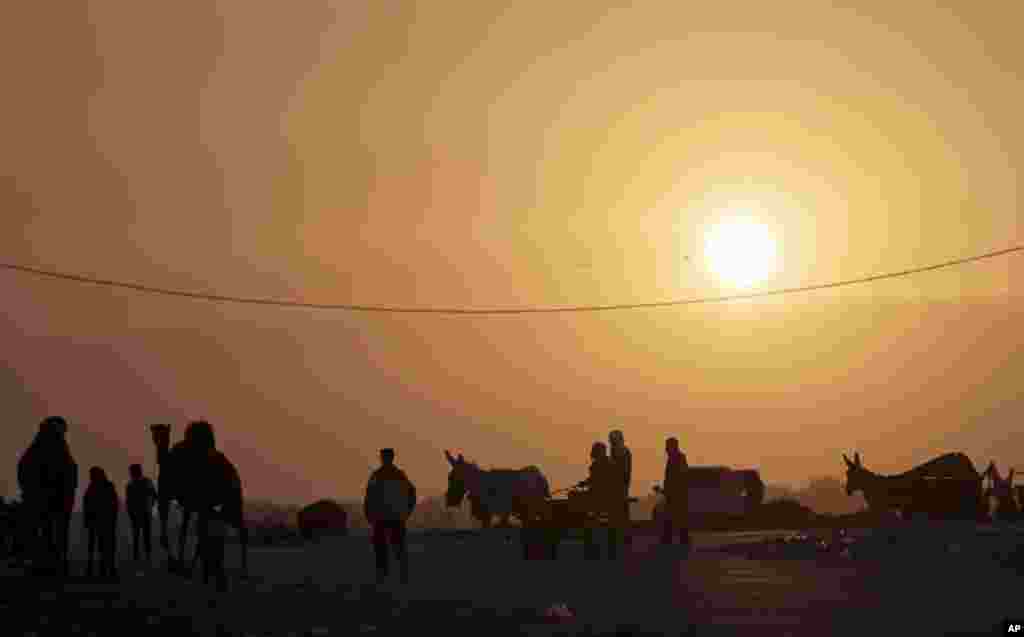 Palestinian residents of the damaged Nada Towers residential neighborhood walk in the street during sunset in the town of Beit Lahiya, northern Gaza Strip.