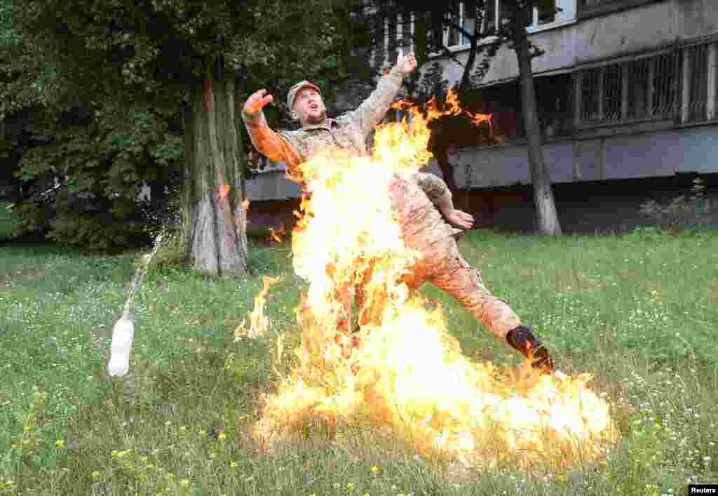 An officer on duty attempts to knock down the flame as Ukrainian former serviceman Serhii Ulianov sets himself on fire while protesting against his dismissal from the Armed Forces in front of the Ukrainian Defense Ministry headquarters in Kiev, Ukraine.