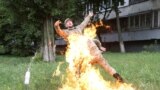 An officer on duty attempts to knock down the flame as Ukrainian former serviceman Serhii Ulianov sets himself on fire while protesting against his dismissal from the Armed Forces in front of the Ukrainian Defense Ministry headquarters in Kiev, Ukraine.