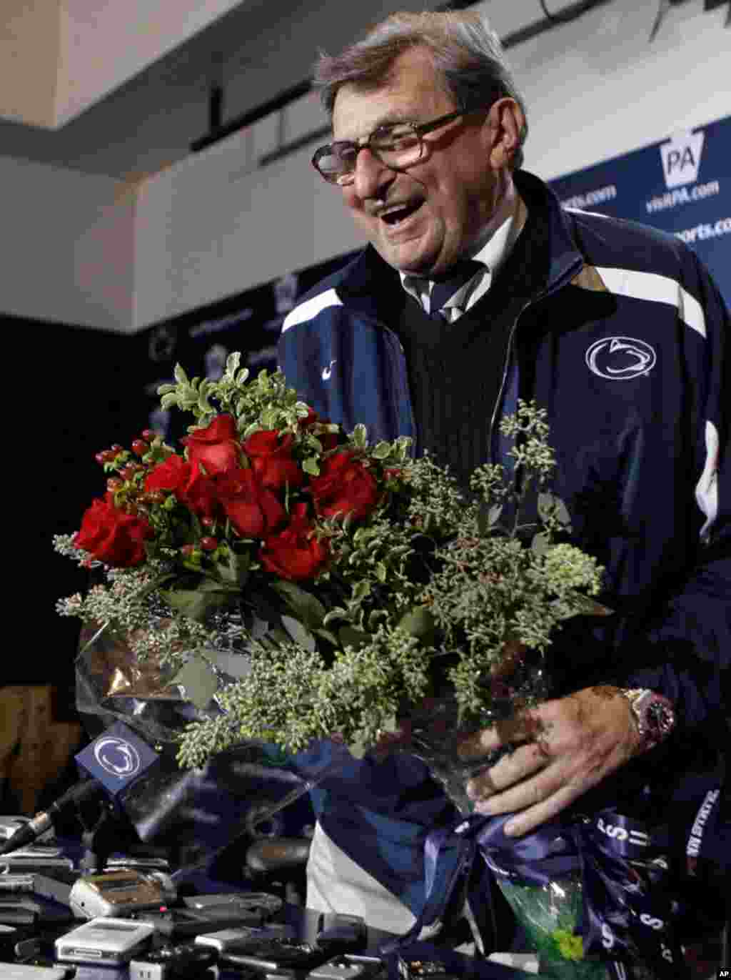 Penn State coach Joe Paterno holds a bouquet of roses presented to him by Ronald Conzonire, a representative from the Roses Bowl, after Penn State won their NCAA college football game against Michigan State 49-18 and the Big Ten Championship in State Coll