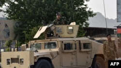 Afghan security personnel stand guard on a Humvee along a road in Kandahar on July 14, 2021. 