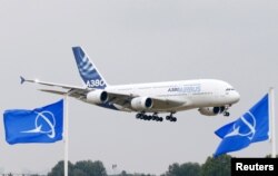 프랑스 파리 공항에서 보잉사 깃발 너머로 비행하는 에어버스 A380 여객기 (자료사진)