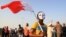 Bahraini anti-government protesters, including a masked boy carrying a national flag, gather for a march in A'ali, Bahrain, April 12, 2013. 