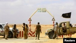 FILE - Militants have been targeting Libyan oil fields and foreign workers. In this March 2014 photo, fighters under Libyan rebel leader Ibrahim Jathran guard the entrance to al-Ghani oil field, which they controlled at the time.