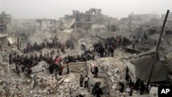 This citizen journalism image from the Aleppo Media Center (AMC) shows people searching debris of destroyed buildings after Syrian government forces airstrike, Jabal Bedro, Aleppo, Feb. 19, 2013.