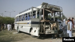 Security officials survey a damaged bus which was hit by a bomb attack in Quetta, Pakistan, June 18, 2012.