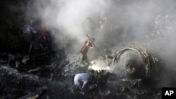 FILE - Volunteers look for survivors of a plane that crashed in a residential area of Karachi, Pakistan, May 22, 2020. 