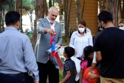 Albanian Prime Minister Edi Rama offers a gift to a boy during his visit to a resort accommodating Afghan refugees in Golem, west of Tirana, Aug. 27, 2021.