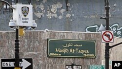 People pass below a New York Police Department security camera, upper left, which is above a mosque on Fulton St., in the Brooklyn neighborhood of Bedford-Stuyvesant in New York, August 18, 2011