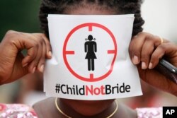FILE- In this July 20, 2013, file photo, a woman protests against underage marriage in Lagos, Nigeria.