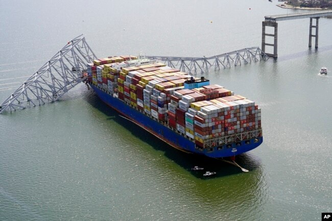 In this aerial image released by the Maryland National Guard, the cargo ship Dali is stuck under part of the structure of the Francis Scott Key Bridge after the ship hit the bridge, Tuesday, March 26, 2024, in Baltimore. (Maryland National Guard via AP)