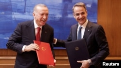 Greek Prime Minister Kyriakos Mitsotakis, right, and Turkish President Recep Tayyip Erdogan smile after signing a joint declaration to pursue good relations, at the Maximos Mansion in Athens, Greece, on Dec. 7, 2023. (Greek Prime Minister’s Office via Reuters)