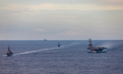 FILE - Japan Maritime Self-Defense Force training ships JS Kashima and JS Shimayuki conduct a passing exercise (PASSEX) with Nimitz-class nuclear-powered aircraft carrier USS Ronald Reagan in the South China Sea, July 7, 2020.