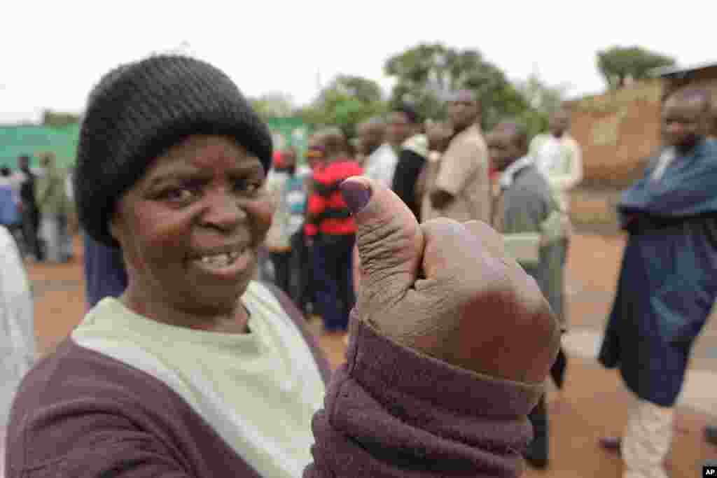 A woman shows her ink stained thumb after casting her vote on Presidential election day in Lusaka, Tuesday, Jan, 20, 2015.
