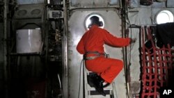 A crew of an Indonesian Air Force C-130 airplane of the 31st Air Squadron, looks out of the window during a search operation for the missing AirAsia flight 8501 jetliner over the waters of Karimata Strait in Indonesia, Monday, Dec. 29, 2014.