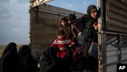 Mujeres y niños salen de un camión parte de un convoy de cientos de personas que están evacuando el último bastión de ISIS en Baghouz, este de Siria, el viernes, 22 de febrero de 2019.