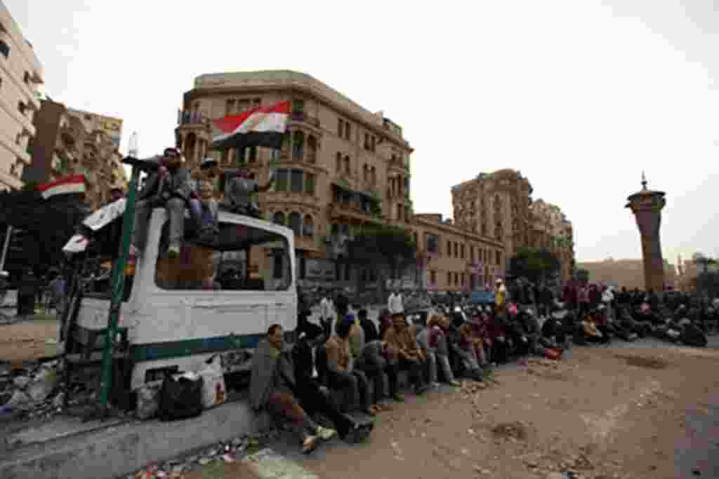 Egyptian anti-government demonstrators gather next to a makeshift barricade at Cairo's Tahrir square as protesters were preparing to mass on the eleventh day for sweeping "departure day" demonstrations, February 4, 2011