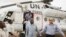 A member of the joint U.N. African Union Mission in Darfur (UNAMID), right, escorts three freed humanitarian workers out of a U.N. helicopter as they landed in El Fasher, North Darfur, Sudan, Saturday, July 19, 2014.