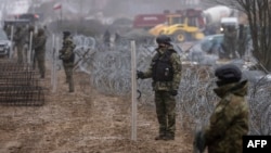 FILE - Border guard officers stand with shields during the construction of a wall along the Polish-Belarusian border in Tolcze, Poland, Jan. 27, 2022. Prime Minister Donald Tusk said on Oct. 12, 2024, the country plans to temporarily suspend the right to asylum for migrants.