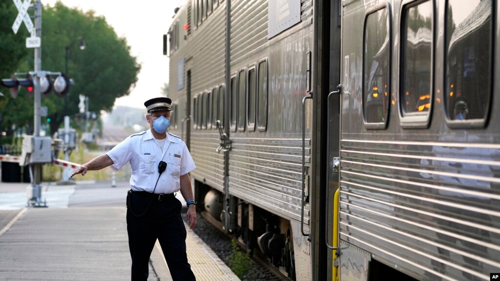 2022 年 9 月 15 日，在伊利诺伊州阿灵顿高地的梅特拉阿灵顿高地站，一名客运火车列车员发出放行信号。（美联社照片）(photo:VOA)