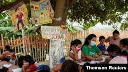 Denisse Toala (vestida de verde) da clases a niños en una escuela improvisada bajo un árbol en el barrio Realidad de Dios, en Guayaquil. Julio 2 de 2020.