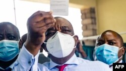 Zimbabwe vice president and Minister of Health Constantino Chiwenga holds up his vaccination certificate after receiving the first shot of Sinopharm in the southern African country which received a donation of 200 000 doses of the COVID-19 vaccine from Ch