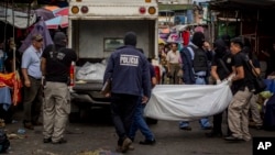 Police investigators carry a body to a forensic vehicle after a shootout between private security guards and gang members at the central market in San Salvador, El Salvador, March 15, 2017. At least 30 people, mostly gang members, died in the last 24 hours in El Salvador on one of the most violent days so far this year. 