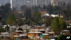 FILE - Makeshift homes fill the Vila Ermita de San Antonio neighborhood, below, near high-rise apartments located in the Las Condes sector of Santiago, Chile.