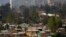 FILE - Makeshift homes fill the Vila Ermita de San Antonio neighborhood, below, near high-rise apartments located in the Las Condes sector of Santiago, Chile.