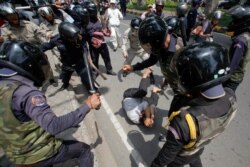 FILE - Security forces beat a man during an International Workers' Day rally in Phnom Penh, May 1, 2014. Authorities broke up a protest of garment workers and opposition party supporters who were marking the event despite a ban on public assemblies.