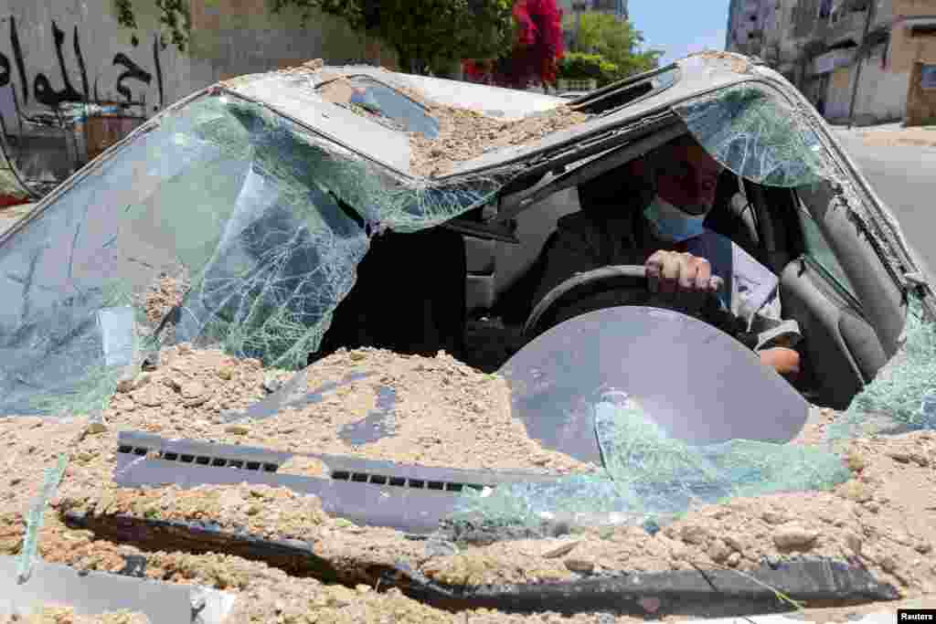 A Palestinian man drives his car, which was damaged in an Israeli airstrike, as he heads to a garage, in Gaza City.