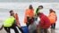 This handout photo taken by Brodie Weeding from The Advocate, Sept. 22, 2020, shows rescuers working to save a pod of whales stranded on a beach in Macquarie Harbor on the rugged west coast of Tasmania, Australia.