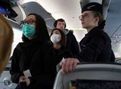 Passengers wear surgical masks as they board a British Airways flight from Terminal 5 at Heathrow Airport in London, March 6, 2020.