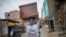 FILE - A worker, a migrant from Venezuela, carries a newly made coffin for victims of COVID-19 to a storeroom at a coffin factory in Lima, Peru, June 4, 2020. 