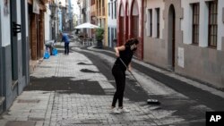 Residents clean the ash from the street in Santa Cruz de la Palma on the Canary island of La Palma, Spain, Sept. 27, 2021. 