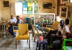 FILE - Sudanese men smoke waterpipes, also known as hookahs, at a cafe in the Sudanese capital Khartoum, Aug. 22, 2019. The consumption of alcohol has recently been decriminalized by Sudan’s transitional government.