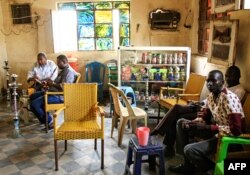 FILE - Sudanese men smoke waterpipes, also known as hookahs, at a cafe in the Sudanese capital Khartoum, Aug. 22, 2019. The consumption of alcohol has recently been decriminalized by Sudan’s transitional government.