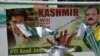 FILE - A Pakistani Kashmiri youth holds Pakistani and Kashmiri flags as he walks past a banner featuring a photograph of Pakistan's Prime Minister Imran Khan, left, during a rally in Muzaffarabad, Sept. 13, 2019. 